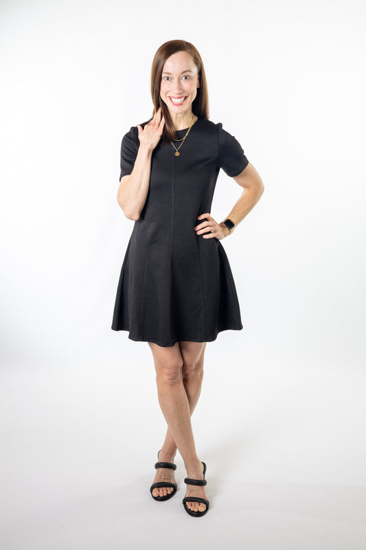Woman wearing a black a-line modal dress on a white background