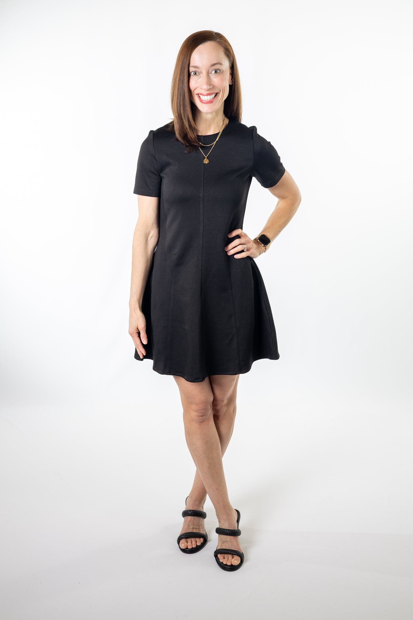 Woman wearing a black mini a-line dress on a white background
