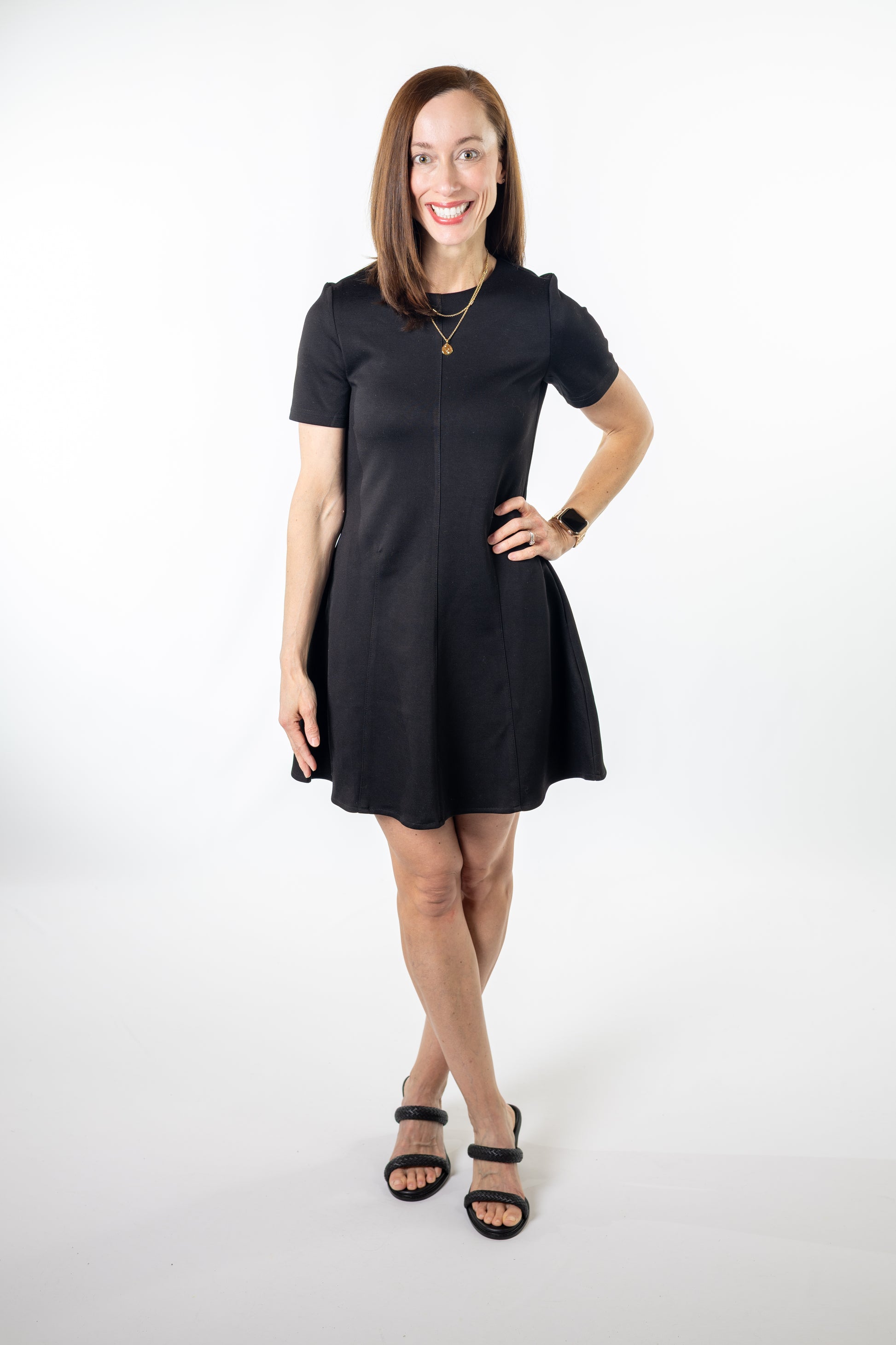 Woman wearing a black mini a-line dress on a white background