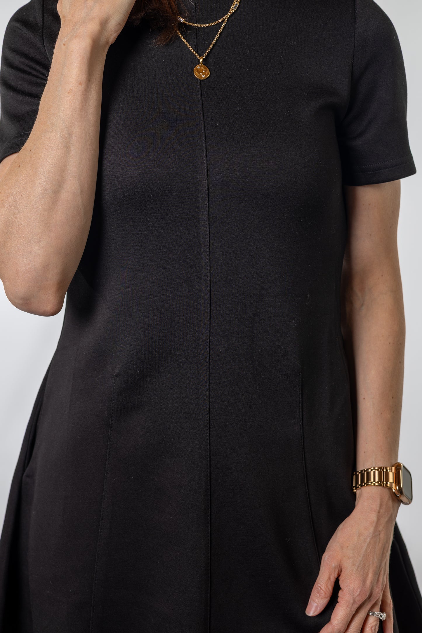 Person wearing a black dress with a plain background