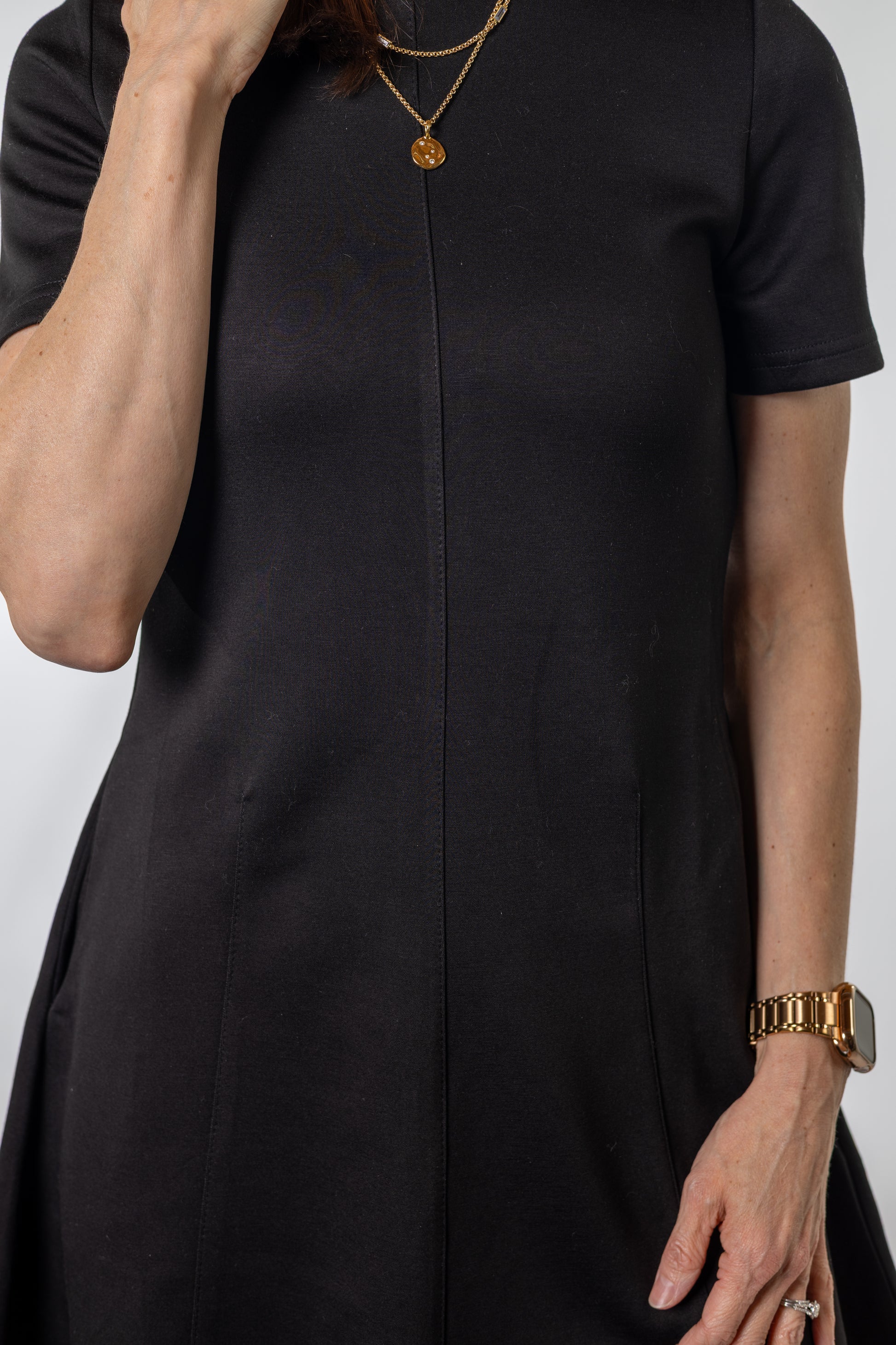 Person wearing a black dress with a plain background