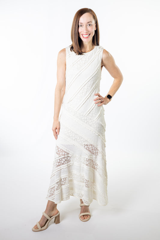 Woman wearing a white sleeveless dress with lace details on a white background