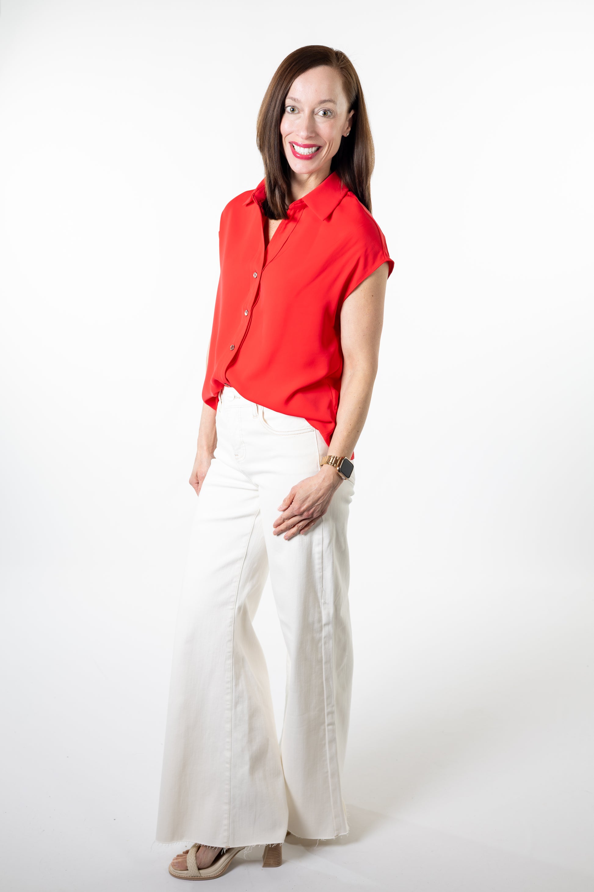 Woman wearing a red blouse and white pants on a white background