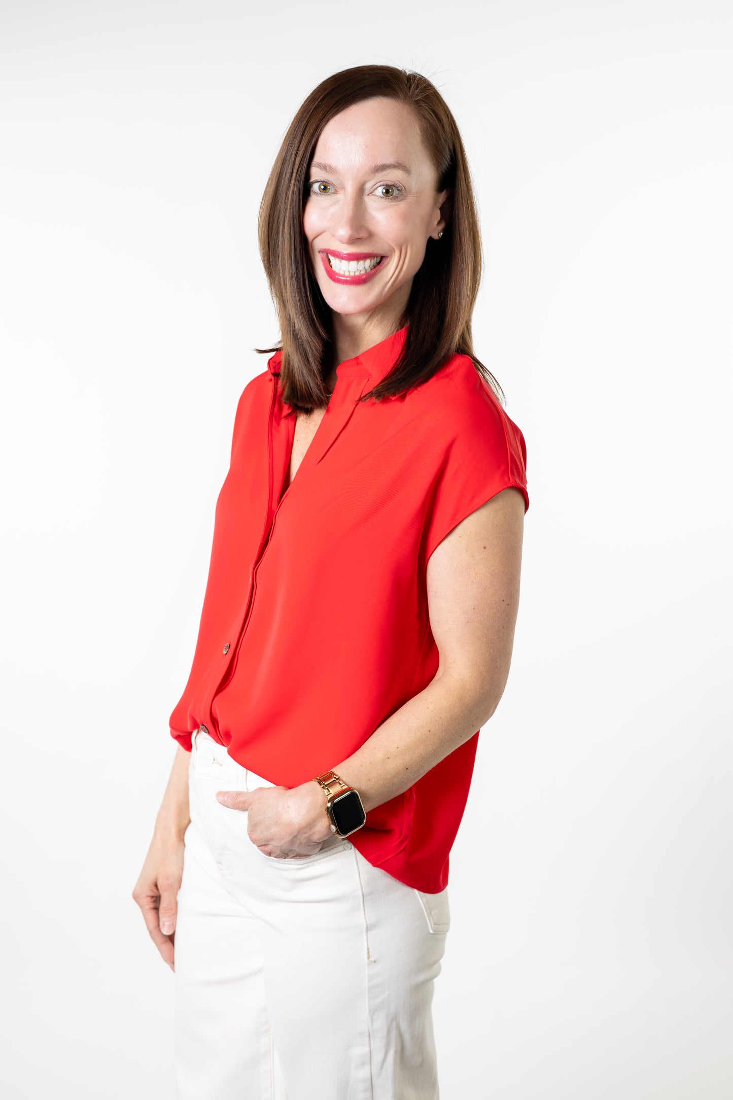 Woman wearing a red blouse and white pants on a white background