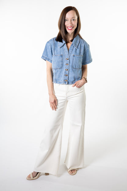 Woman wearing a denim jacket and white pants on a white background