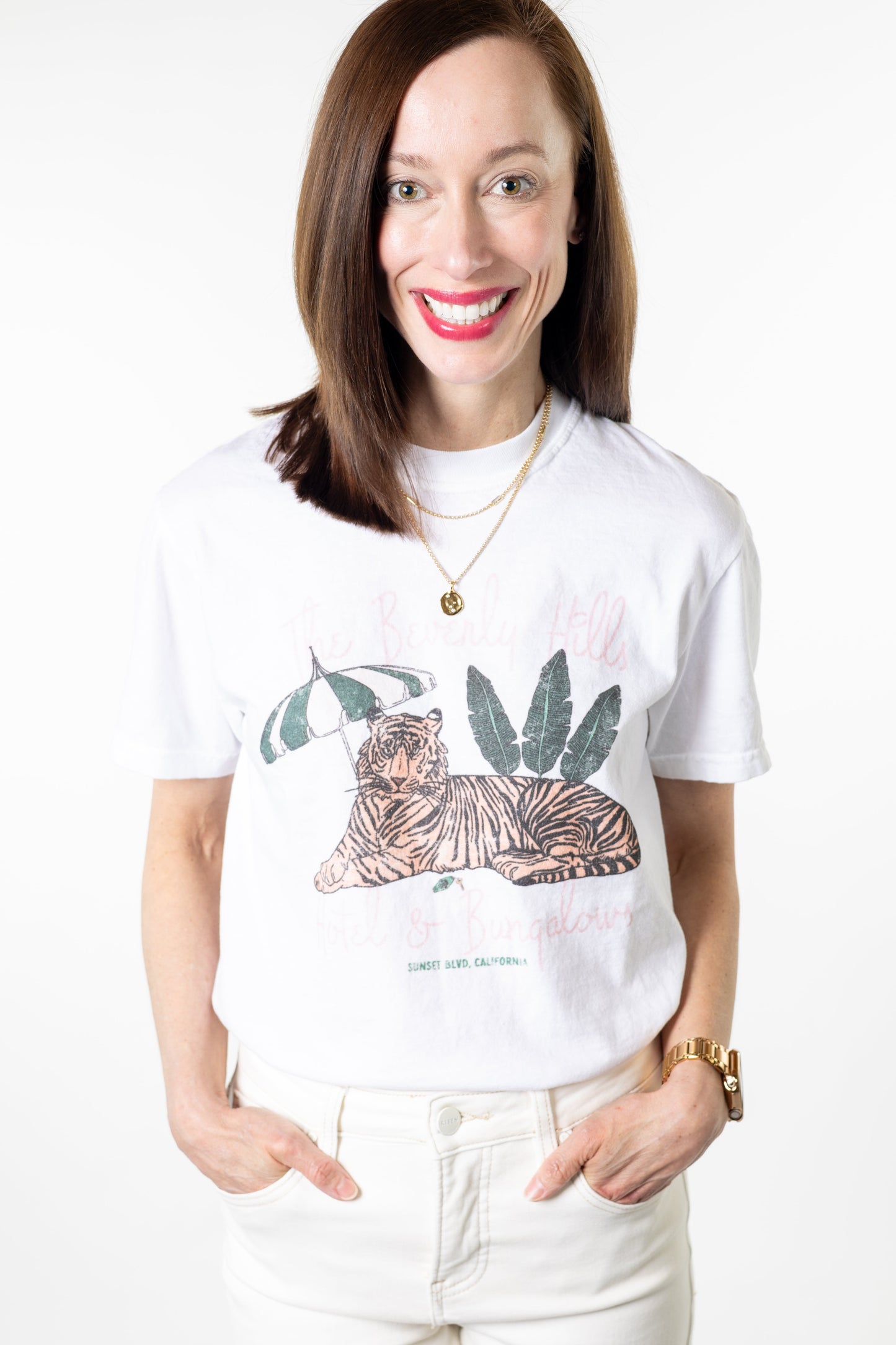 Woman wearing a white t-shirt with a graphic design of a tiger and plants, standing against a white background.