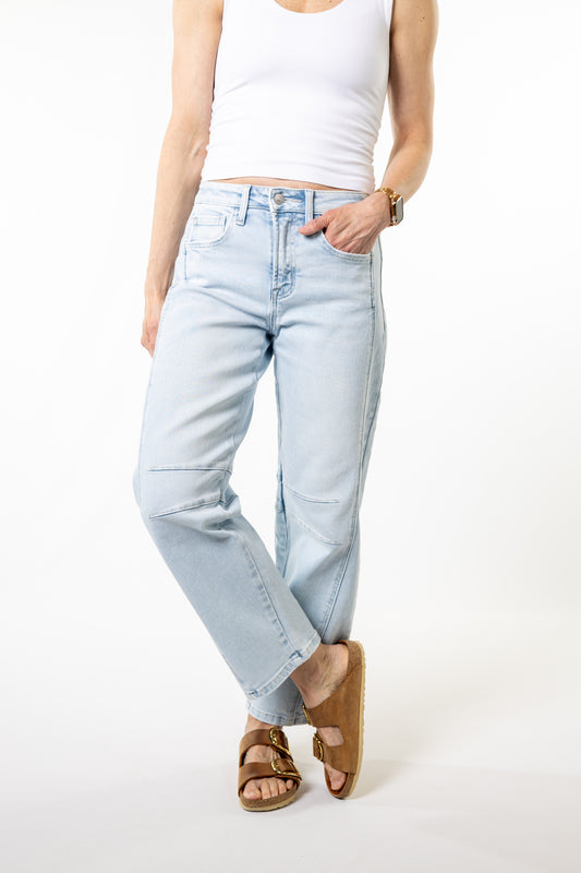 Person wearing light blue barrel jeans and a white top on a white background