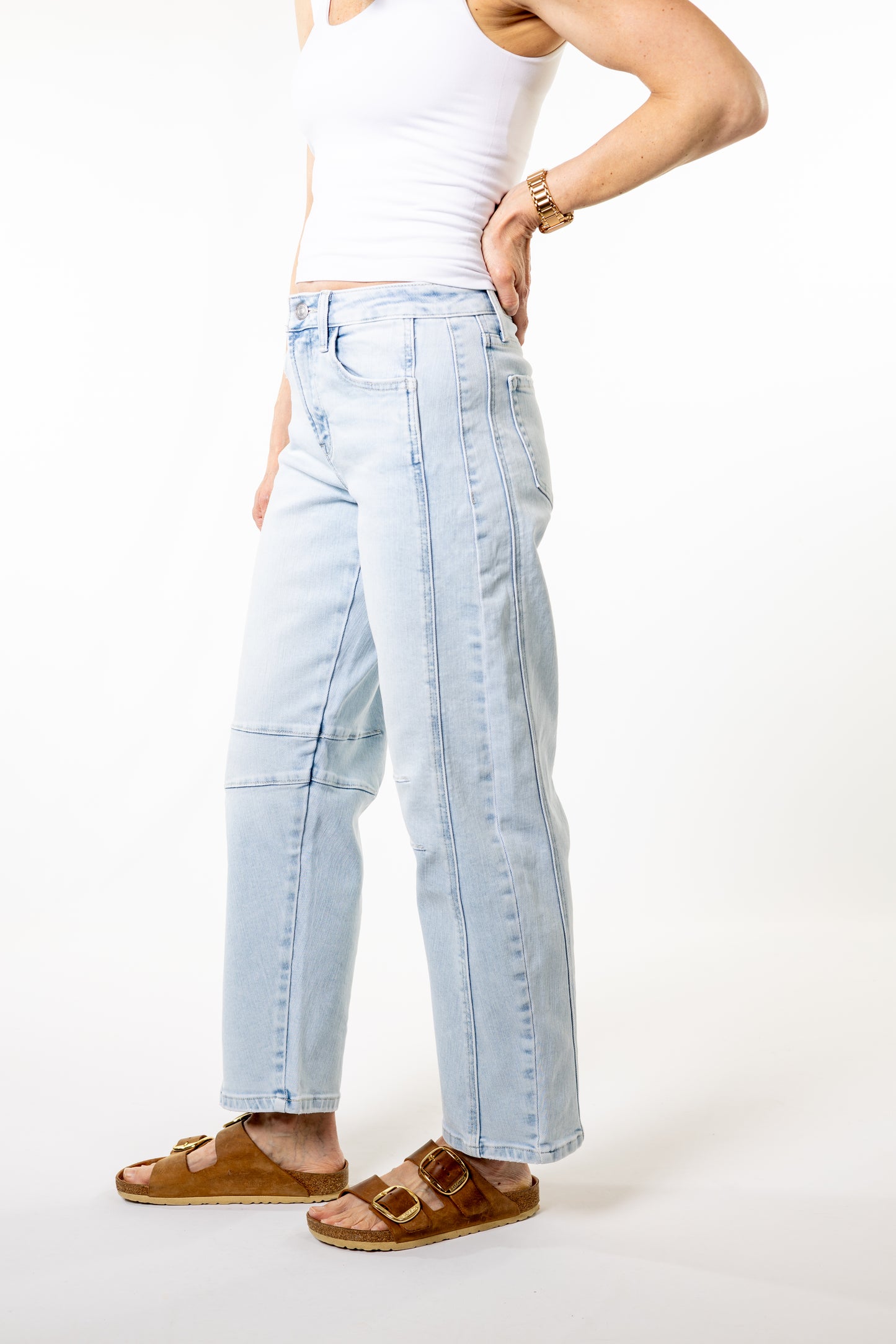 Person wearing light blue jeans and brown sandals on a white background