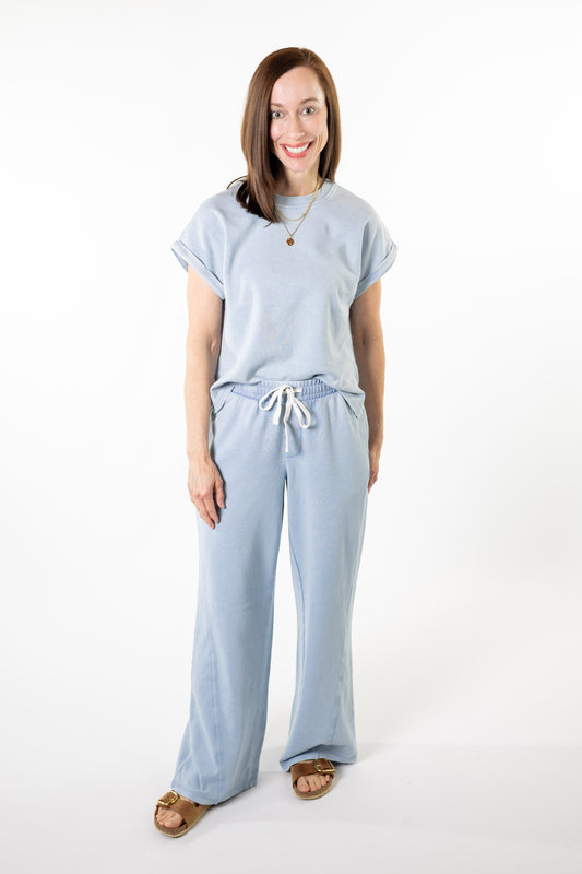 Woman wearing a light blue outfit with a matching top and pants on a white background
