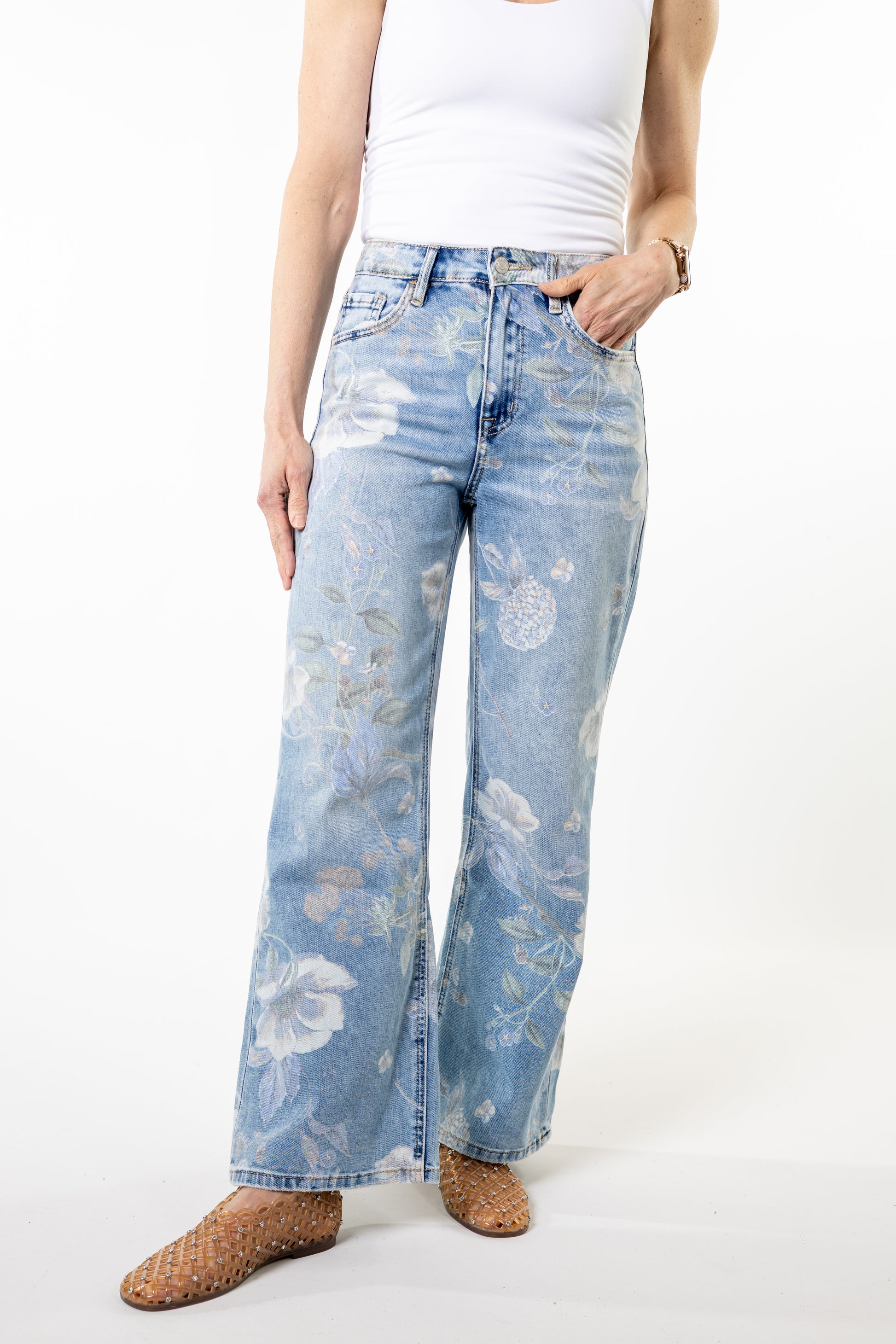 Person wearing light blue floral jeans on a white background