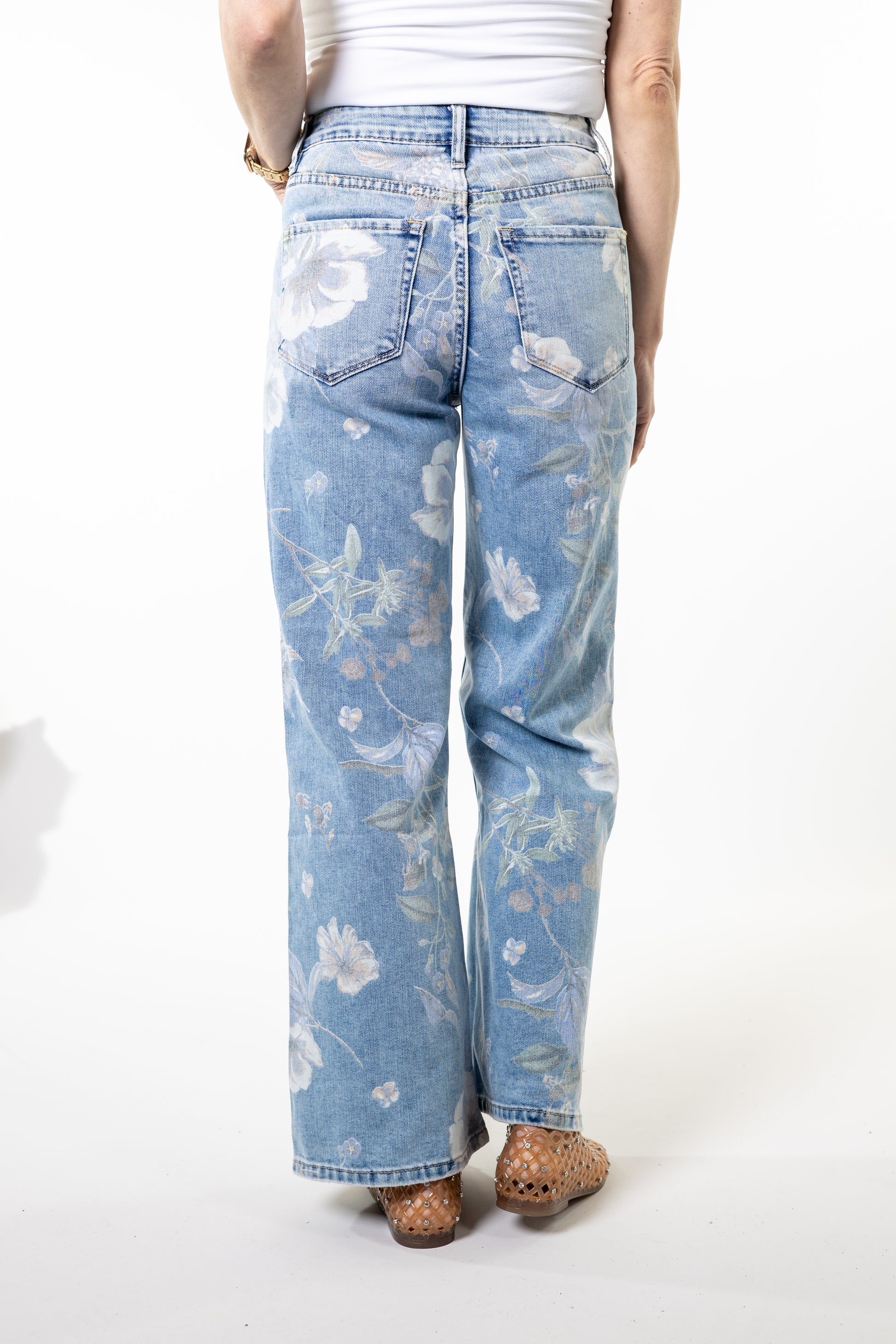 Light blue jeans with floral patterns worn by a person on a white background