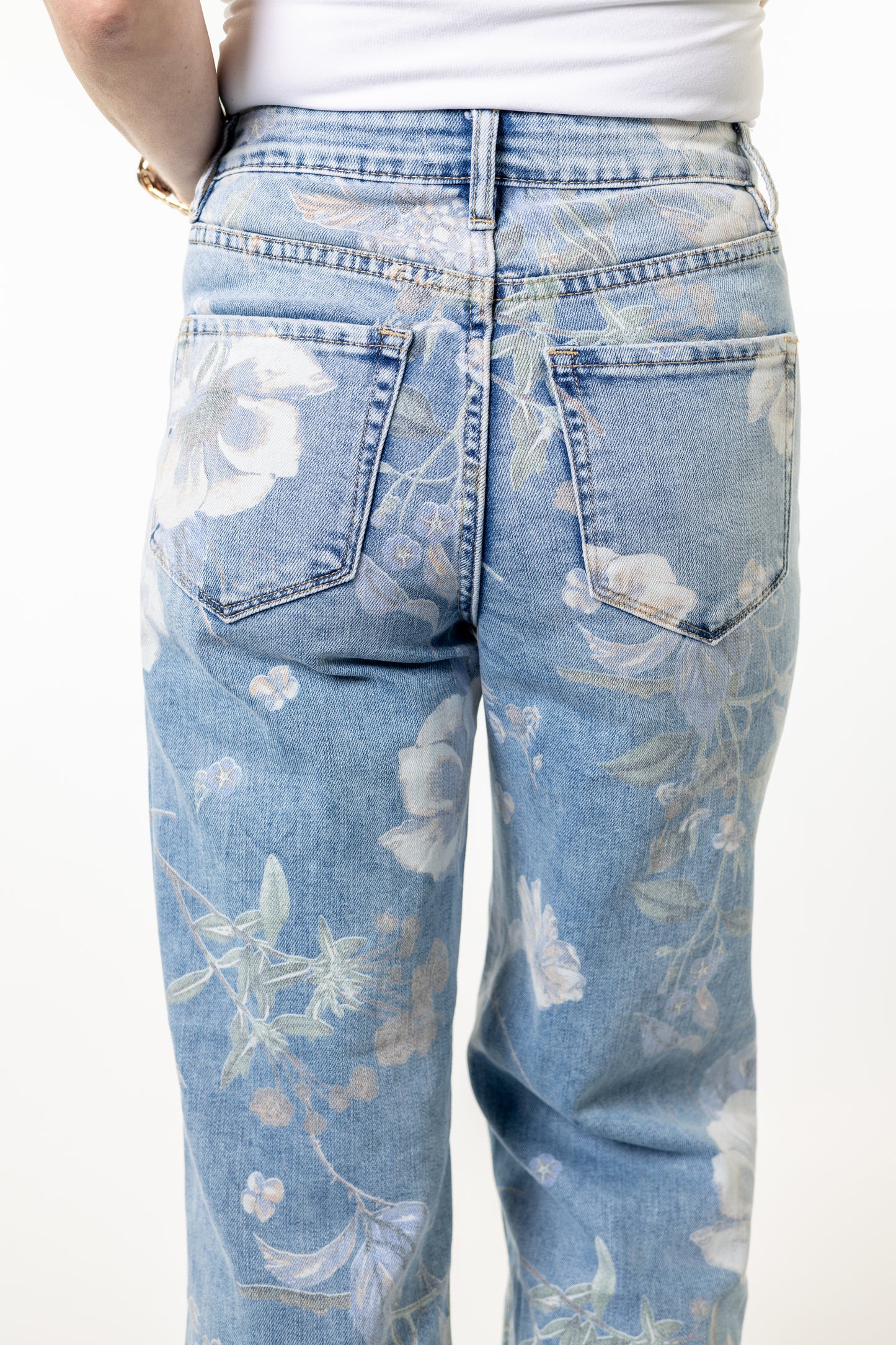 Light blue jeans with floral pattern worn by a person on a white background