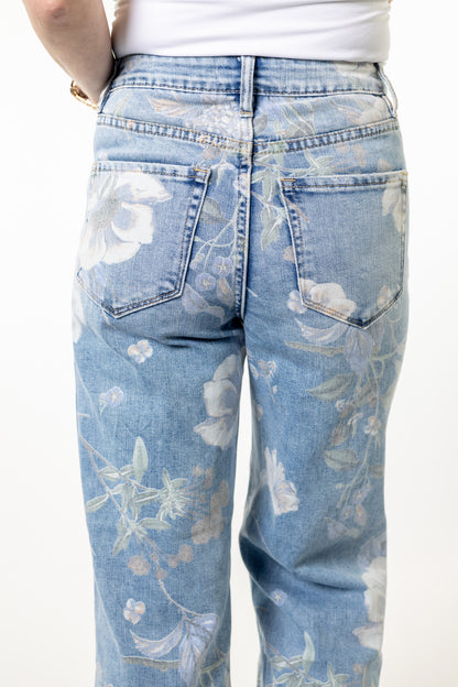 Light blue jeans with floral pattern worn by a person on a white background