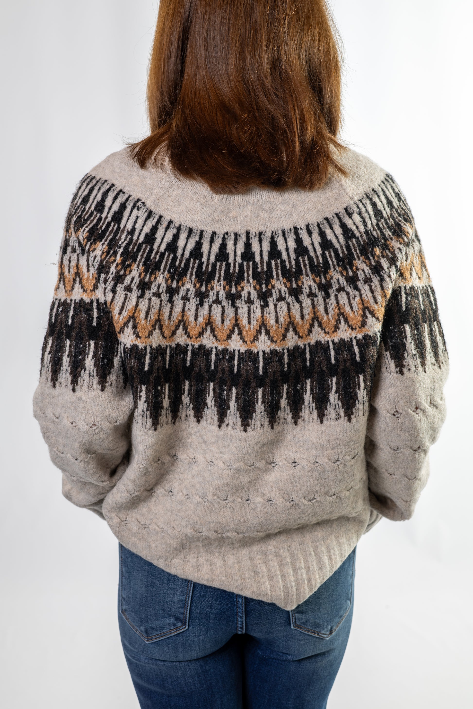 Person wearing a nordic patterned sweater with a plain background