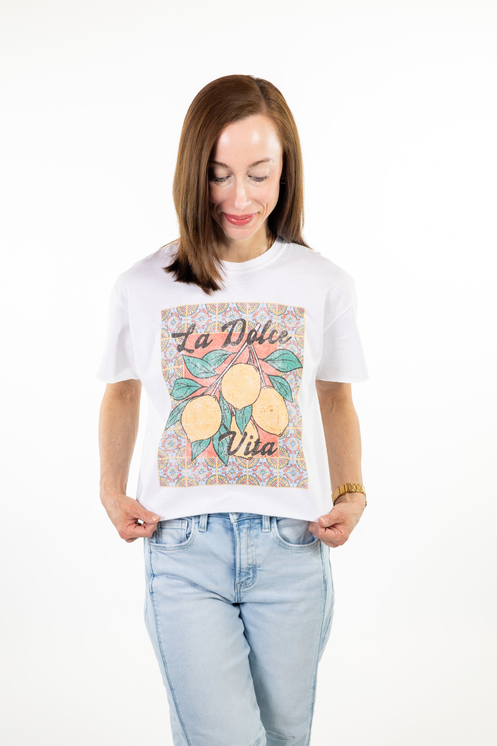 Woman wearing a white la dolce lemon t-shirt with a graphic design on a white background