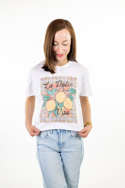 Woman wearing a white la dolce lemon t-shirt with a graphic design on a white background