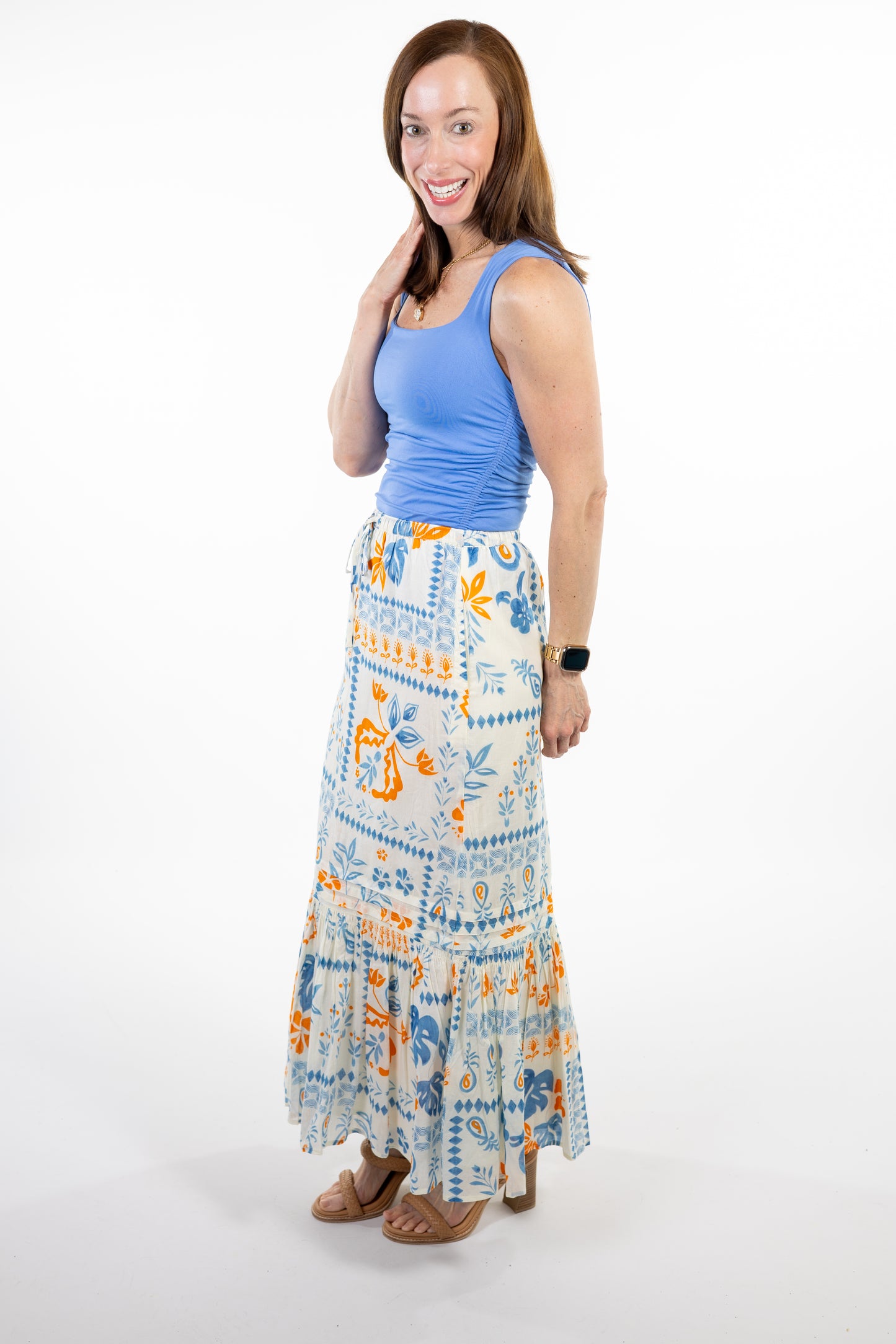 Woman wearing a blue top and patterned skirt on a white background