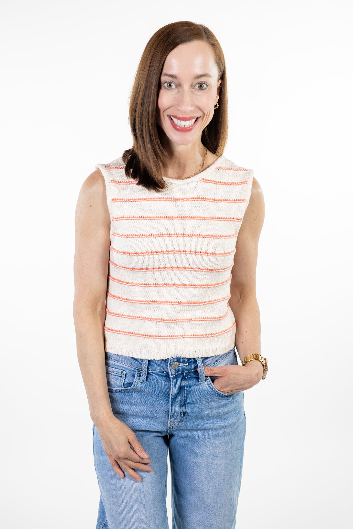 Woman wearing cream knit tank with coral stripes and jeans