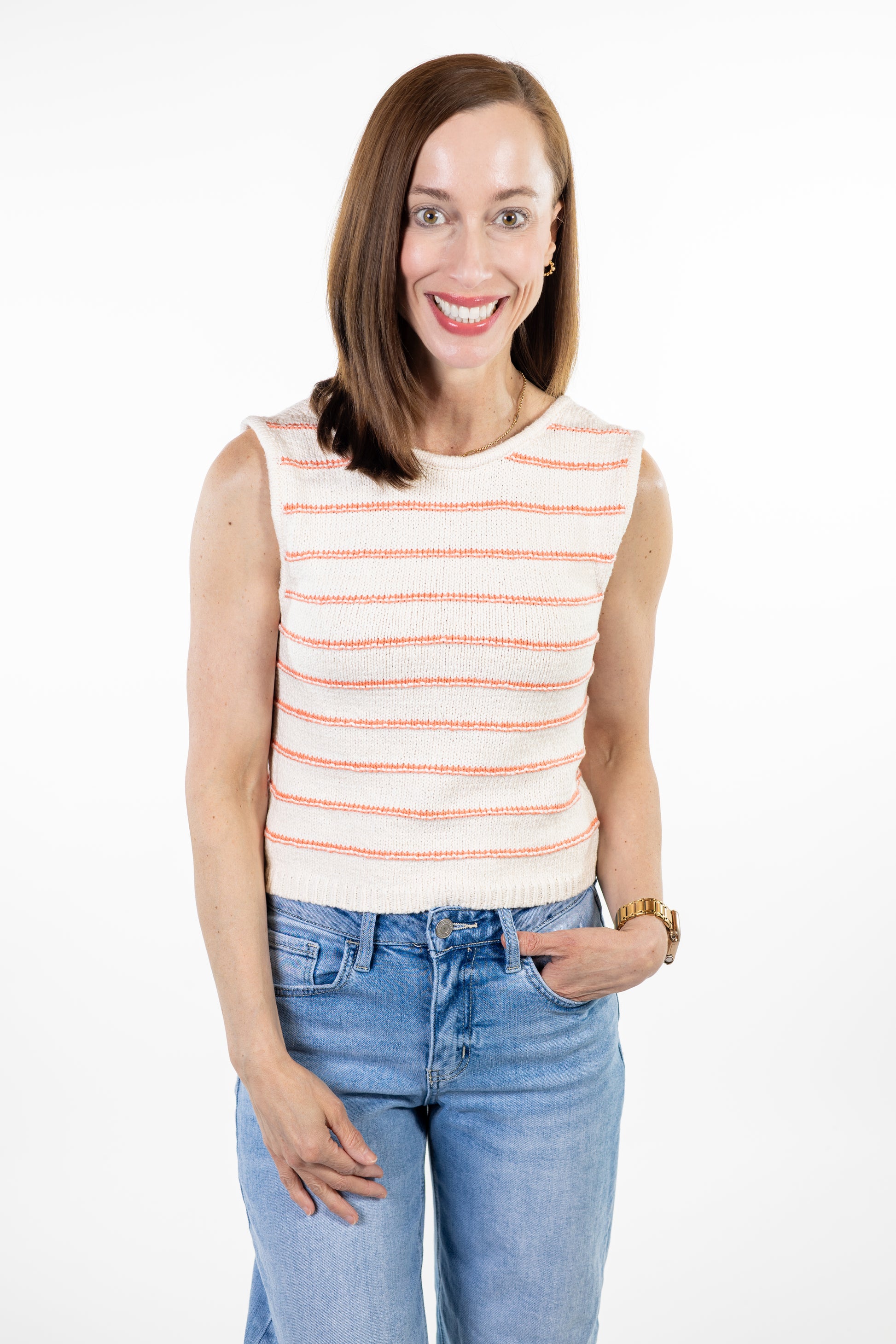 Woman wearing cream knit tank with coral stripes and jeans