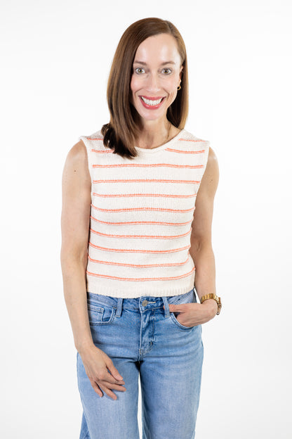 Woman wearing cream knit tank with coral stripes and jeans