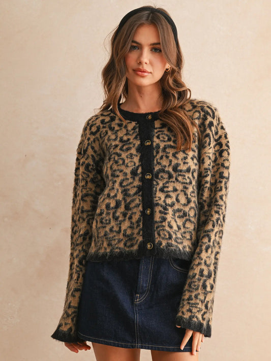 Woman wearing a leopard print cardigan over a black top with a denim skirt on a beige background
