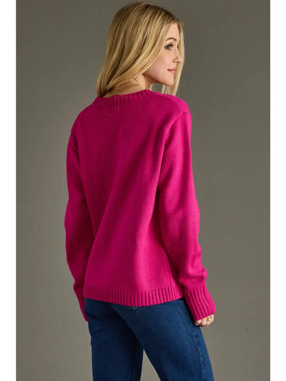 Woman wearing a bright pink sweater and blue jeans against a gray background