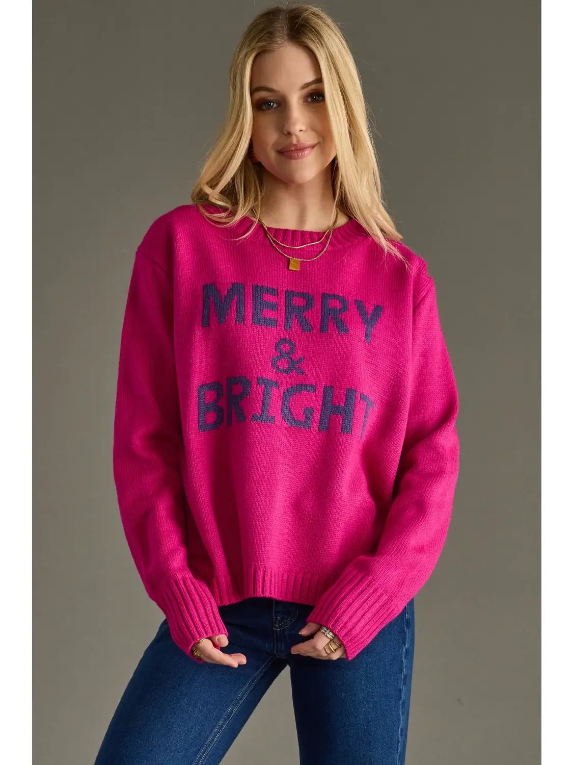 Woman wearing a pink sweater with 'Merry & Bright' text on a gray background