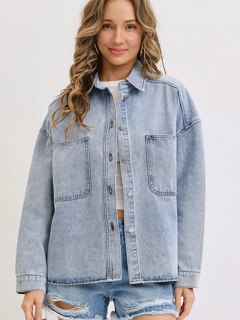 Woman wearing a light blue denim jacket on a plain background