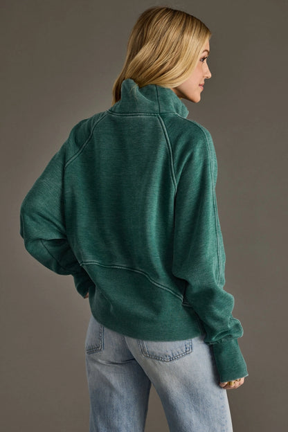 Person wearing a green fleece jacket and light blue jeans against a gray background